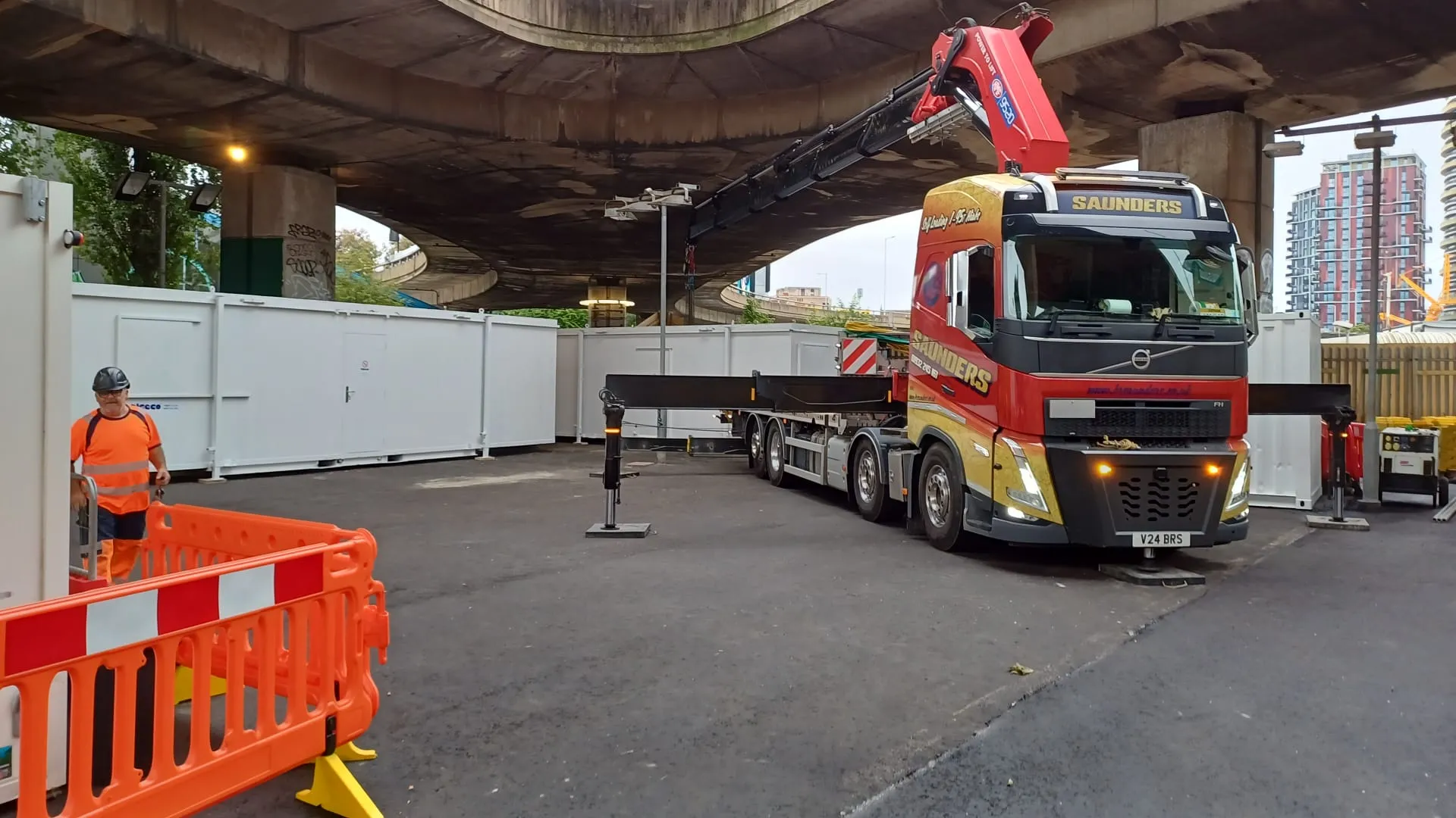 A man standing next to a large truck under a bridge.